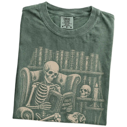 Folded Moss Comfort Colors® T-shirt showing skeleton reading in a library beside a Australian Shepherd