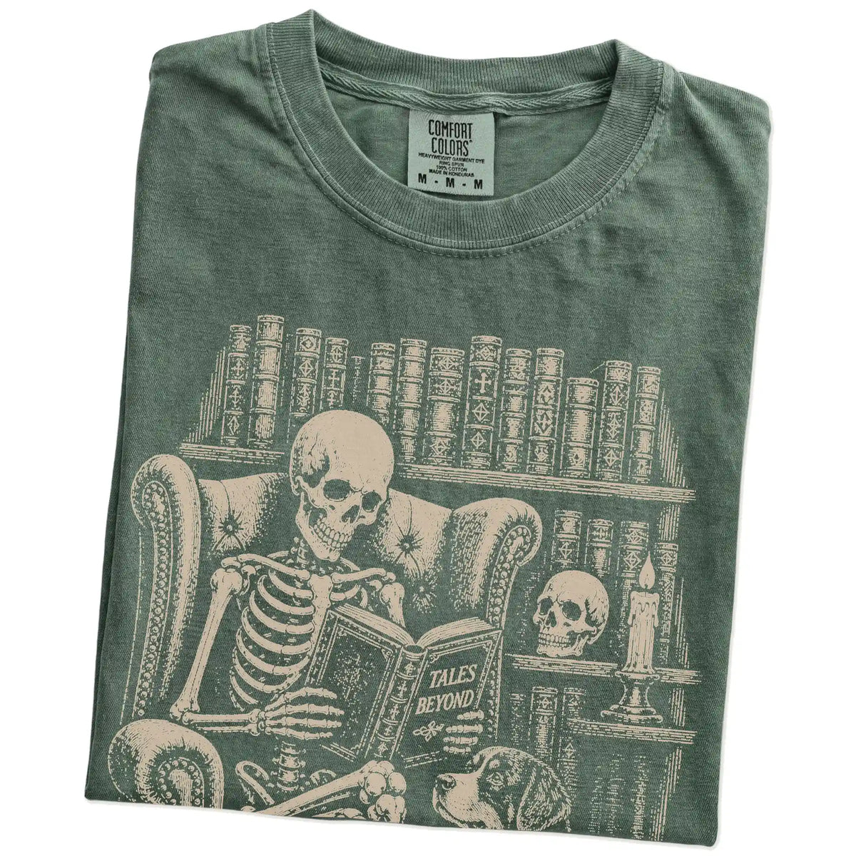 Folded Moss Comfort Colors® T-shirt showing skeleton reading in a library beside a Bernese Mountain Dog