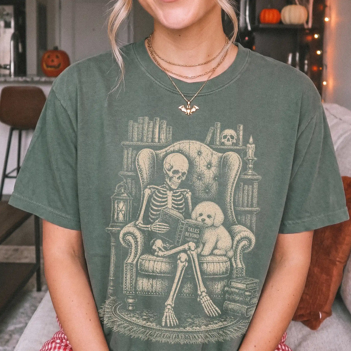 Model wearing a Moss Comfort Colors® T-shirt showing skeleton reading in a library beside a Bichon Frise