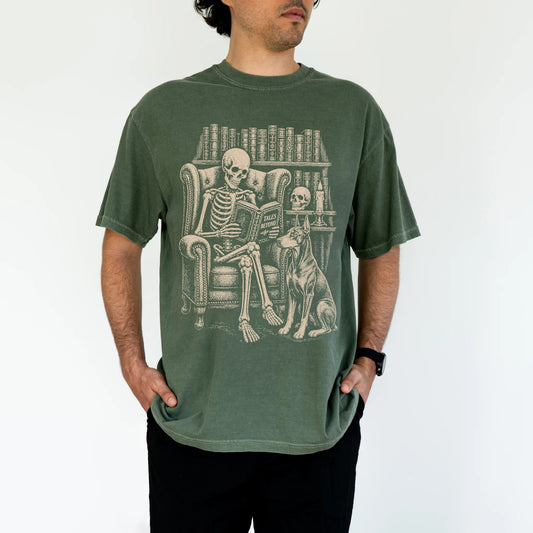 Model wearing a Moss Comfort Colors® T-shirt showing skeleton reading in a library beside a Doberman