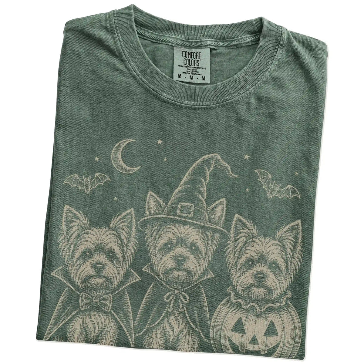 Folded Moss Comfort Colors® T-shirt showing three Yorkie dogs dressed for Halloween beneath bats and a crescent moon