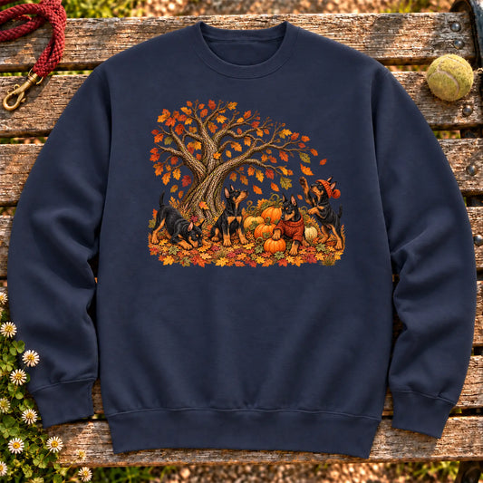 Four Doberman puppies with pumpkins beneath an autumn tree on a Navy crewneck sweatshirt