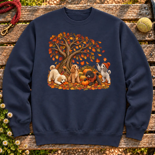 Four Poodle puppies with pumpkins beneath an autumn tree on a Navy crewneck sweatshirt