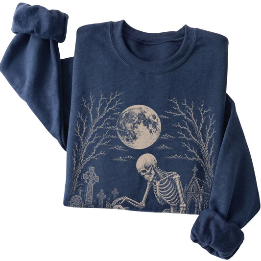 Folded Navy sweatshirt with a skeleton petting a Blue Heeler in a graveyard