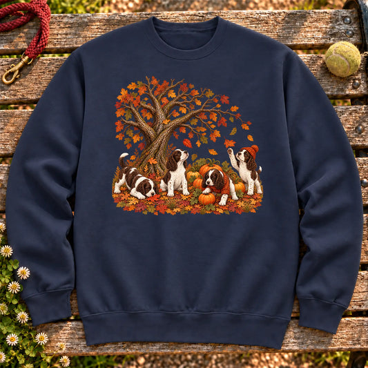 Four Springer Spaniel puppies with pumpkins beneath an autumn tree on a Navy crewneck sweatshirt
