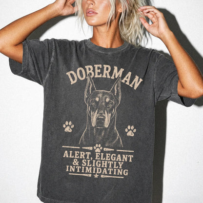 Model wearing a Pepper Comfort Colors® T-shirt featuring Doberman design with “Alert, Elegant & Slightly Intimidating” letter