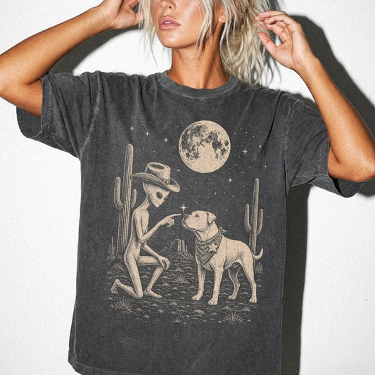 Model wearing a Pepper Comfort Colors® T-shirt with cowboy alien fist-bumping a american bulldog beneath the moon