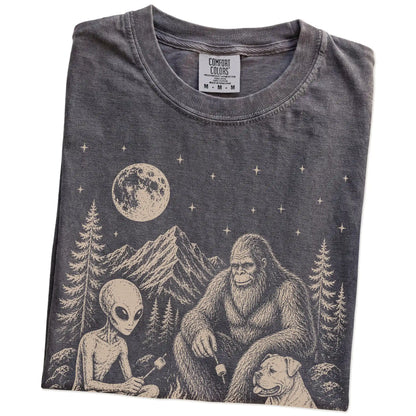 Folded Pepper Comfort Colors® T-shirt showing American Bulldog camping with Bigfoot and an alien