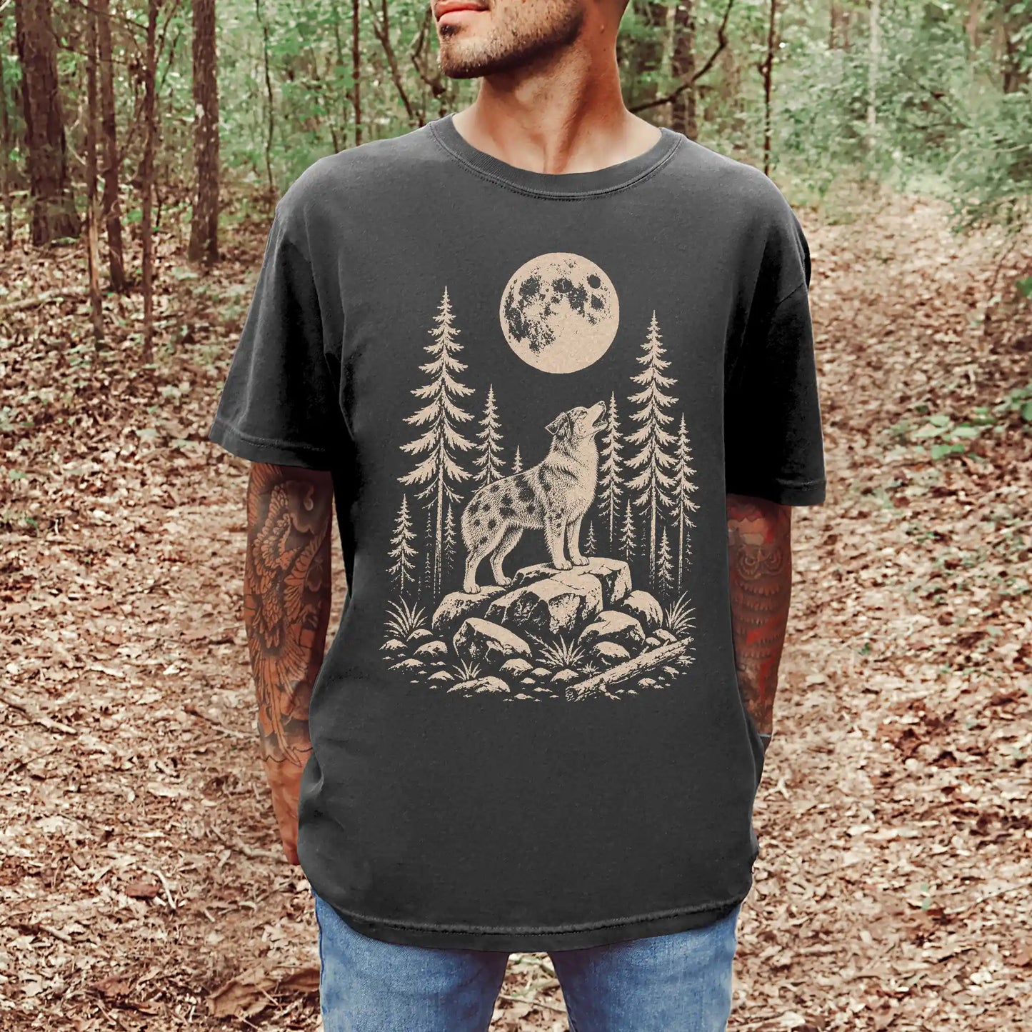 Model wearing a Pepper Comfort Colors® T-shirt with a Australian Shepherd howling beneath the moon and pine trees