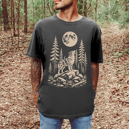 Model wearing a Pepper Comfort Colors® T-shirt with a Australian Shepherd howling beneath the moon and pine trees