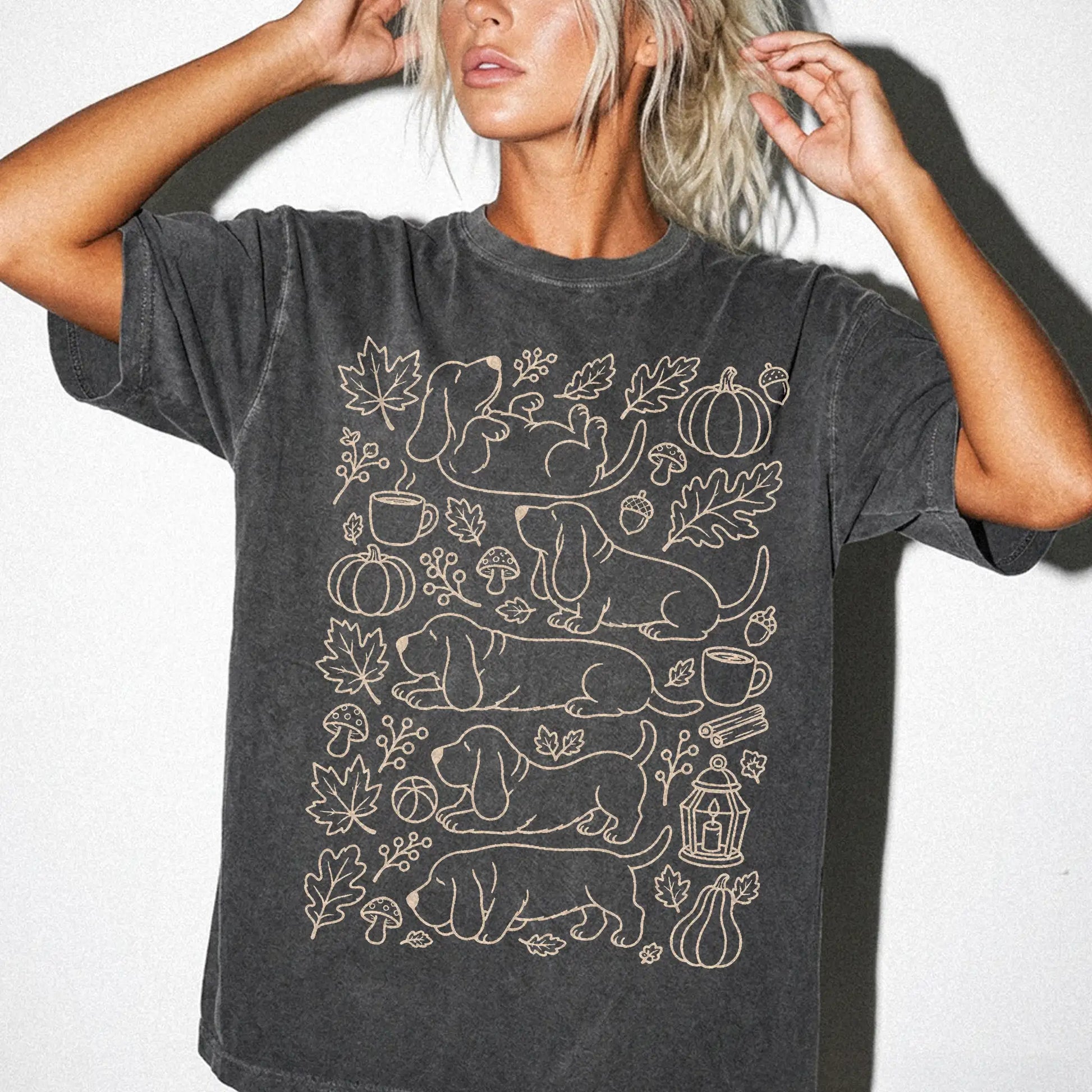 Model wearing a Pepper Comfort Colors® T-shirt with Basset Hound dogs with pumpkins, leaves, acorns, and woodland details