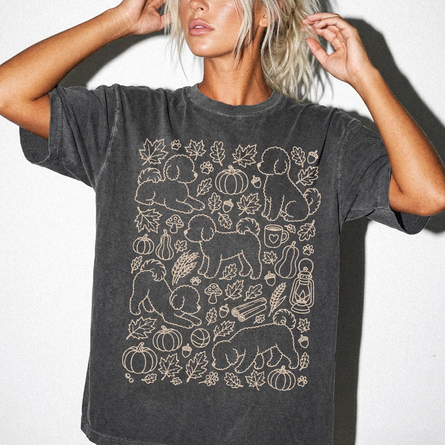 Model wearing a Pepper Comfort Colors® T-shirt with Bichon Frise dogs with pumpkins, leaves, acorns, and woodland details