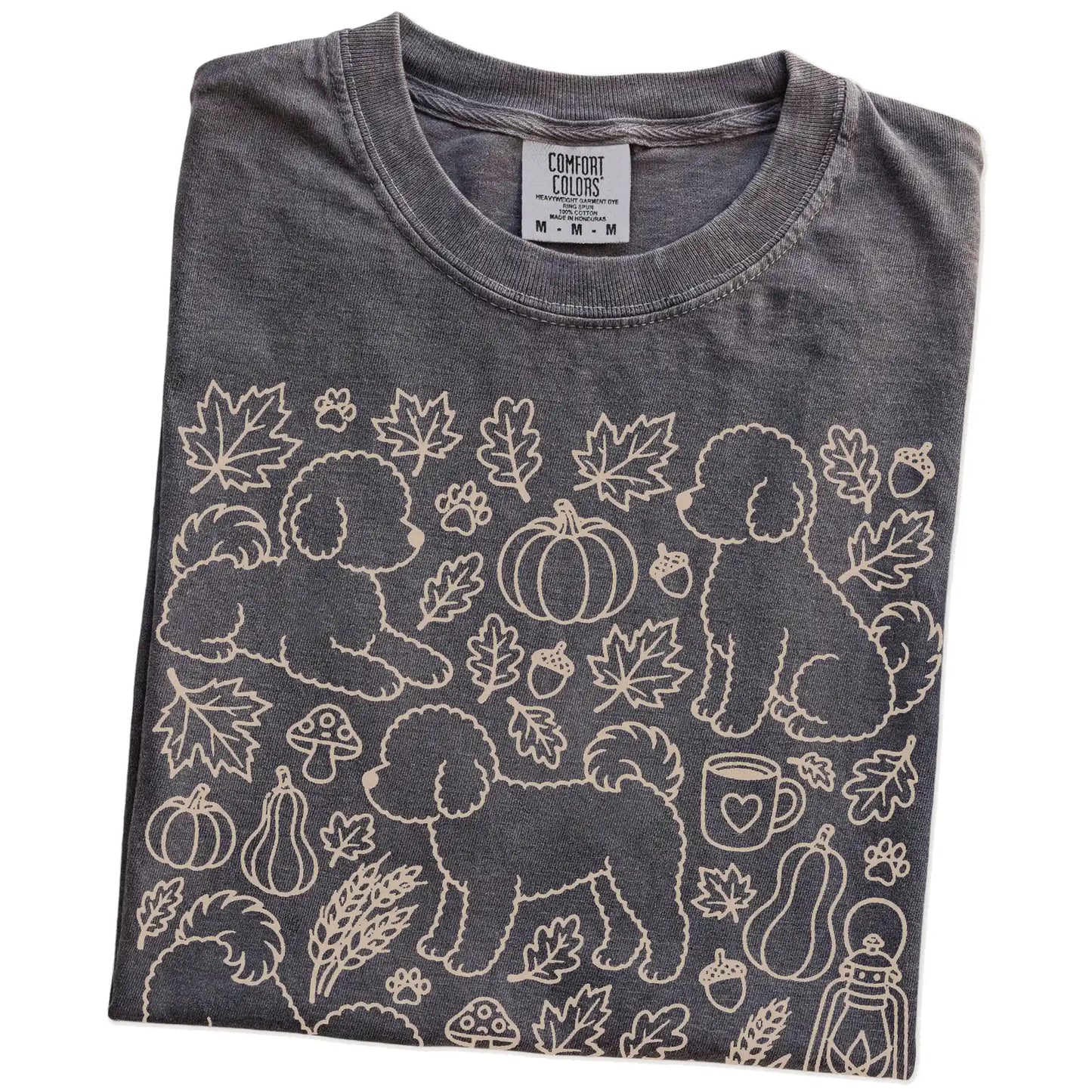 Folded Pepper Comfort Colors® T-shirt showing Bichon Frise dogs with pumpkins, leaves, acorns, and woodland details