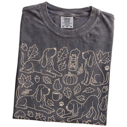 Folded Pepper Comfort Colors® T-shirt showing Bloodhound dogs with pumpkins, leaves, acorns, and woodland details