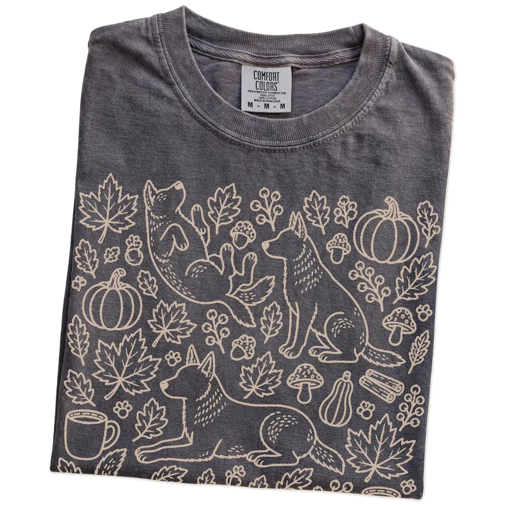 Folded Pepper Comfort Colors® T-shirt showing Blue Heeler dogs with pumpkins, leaves, acorns, and woodland details