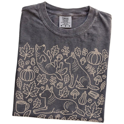 Folded Pepper Comfort Colors® T-shirt showing Blue Heeler dogs with pumpkins, leaves, acorns, and woodland details