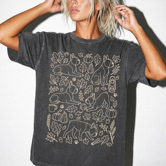 Model wearing a Pepper Comfort Colors® T-shirt with Boston Terrier dogs with pumpkins, leaves, acorns, and woodland details
