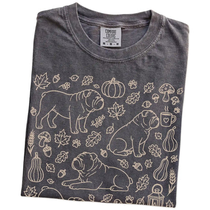 Folded Pepper Comfort Colors® T-shirt showing Bulldog dogs with pumpkins, leaves, acorns, and woodland details
