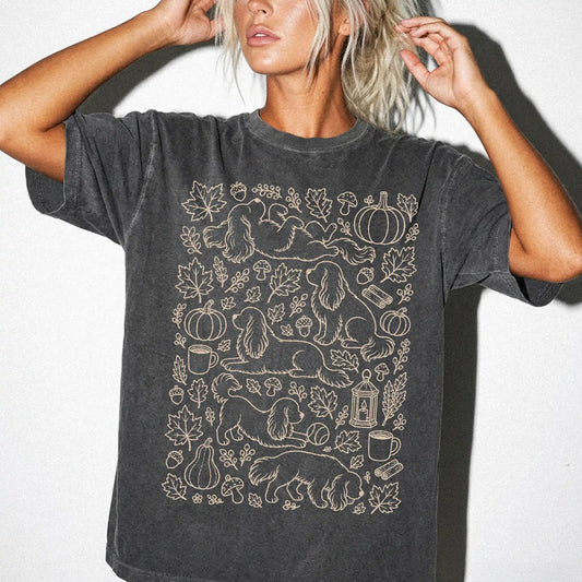 Model wearing a Pepper Comfort Colors® T-shirt with Cavalier King Charles Spaniel dogs with pumpkins, leaves, acorns, and woo