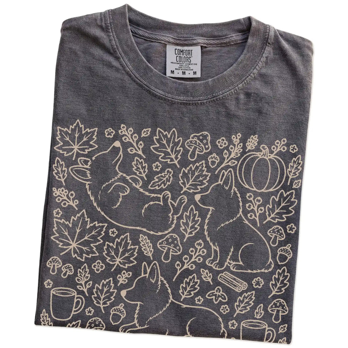 Folded Pepper Comfort Colors® T-shirt showing Corgi dogs with pumpkins, leaves, acorns, and woodland details