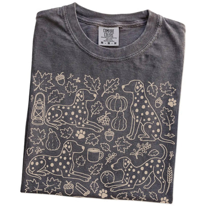 Folded Pepper Comfort Colors® T-shirt showing Dalmatian dogs with pumpkins, leaves, acorns, and woodland details