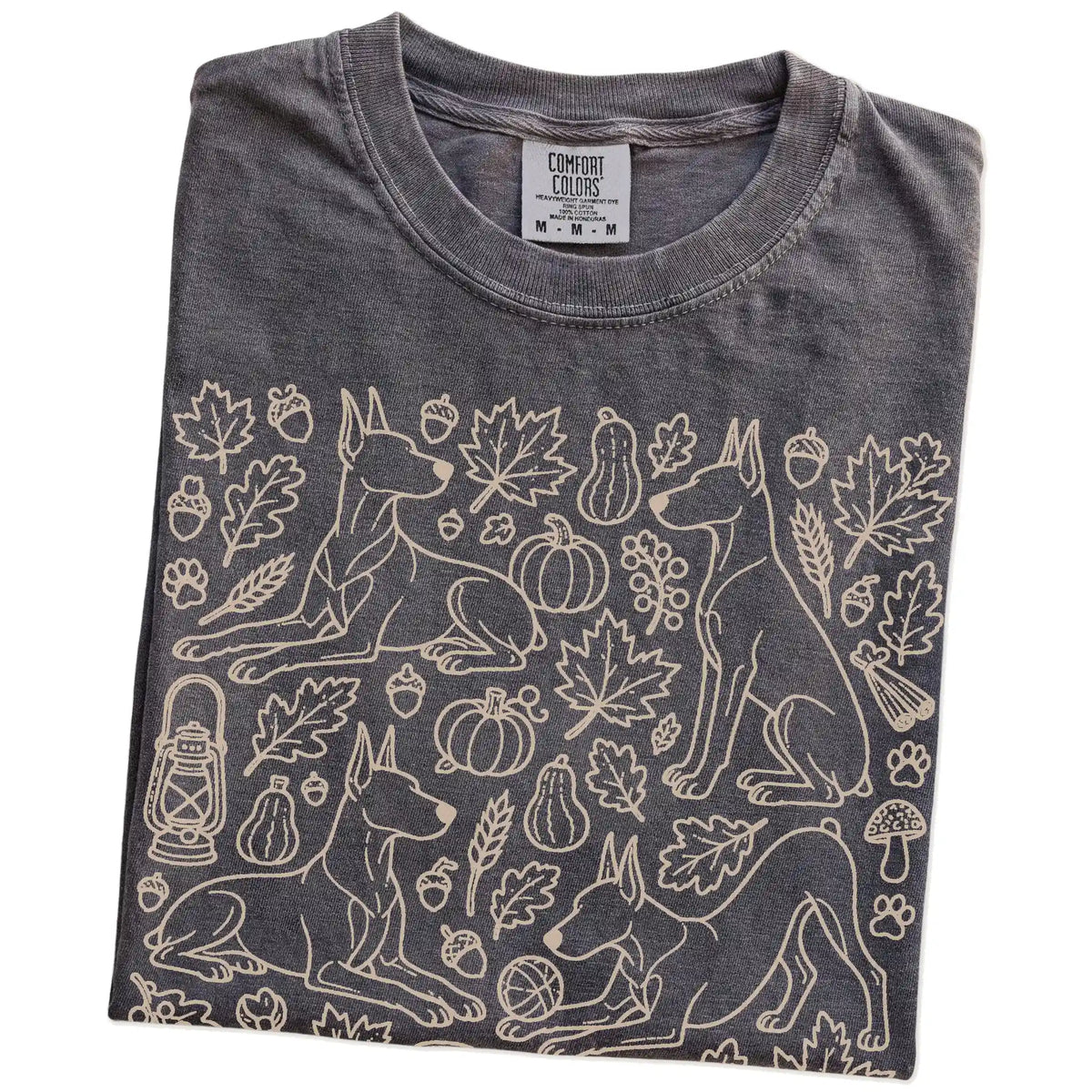 Folded Pepper Comfort Colors® T-shirt showing Doberman dogs with pumpkins, leaves, acorns, and woodland details