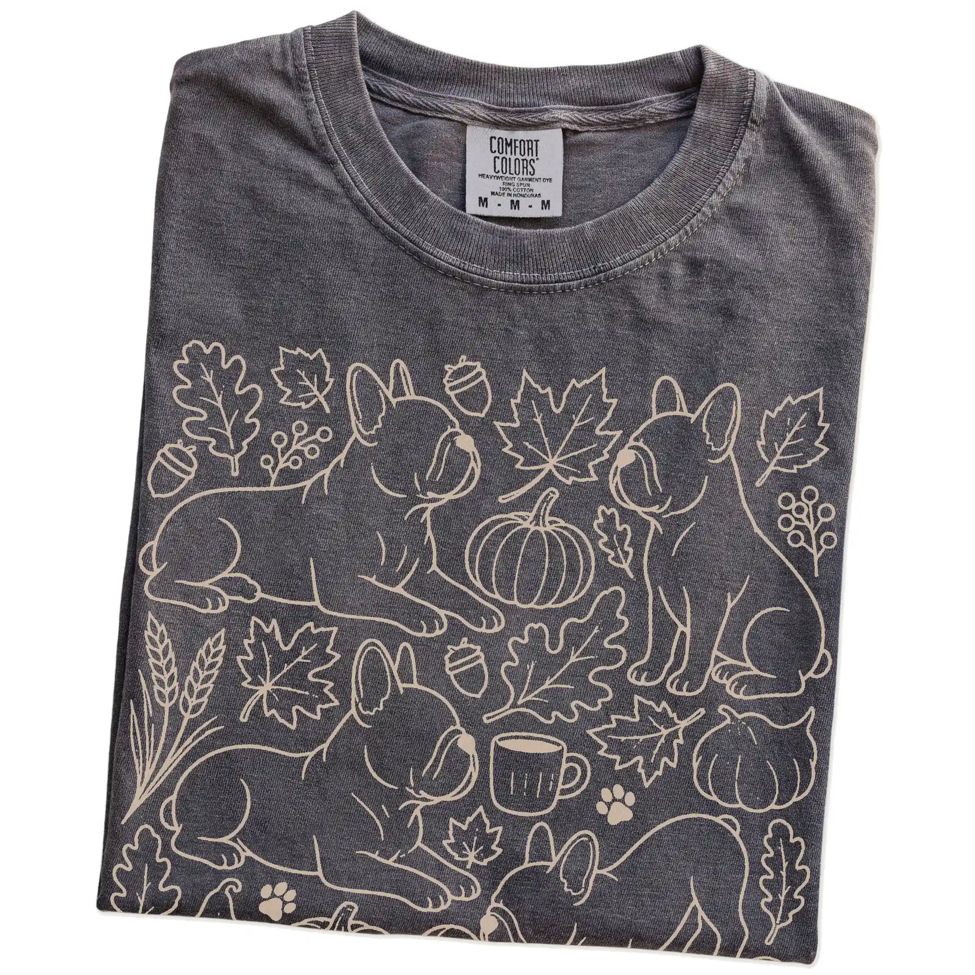 Folded Pepper Comfort Colors® T-shirt showing French Bulldog dogs with pumpkins, leaves, acorns, and woodland details