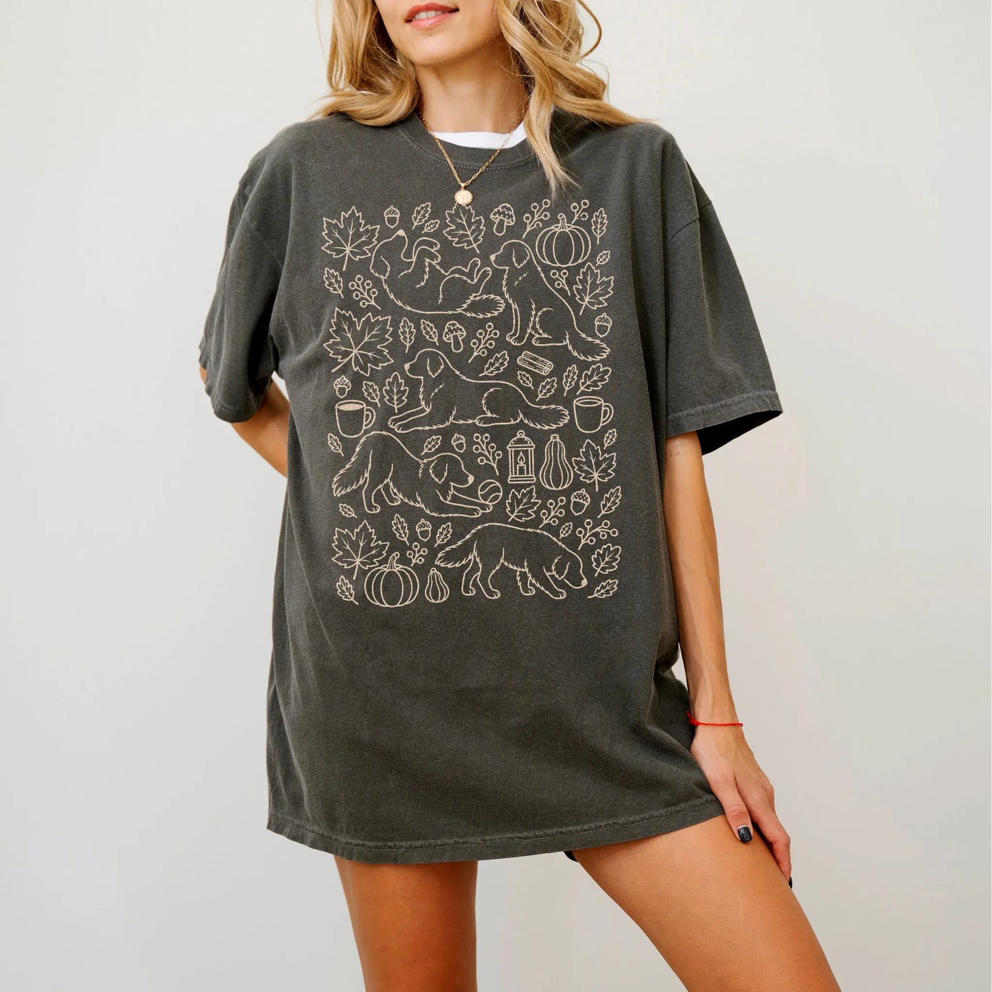 Model wearing a Pepper Comfort Colors® T-shirt with Golden Retriever dogs with pumpkins, leaves, acorns, and woodland details