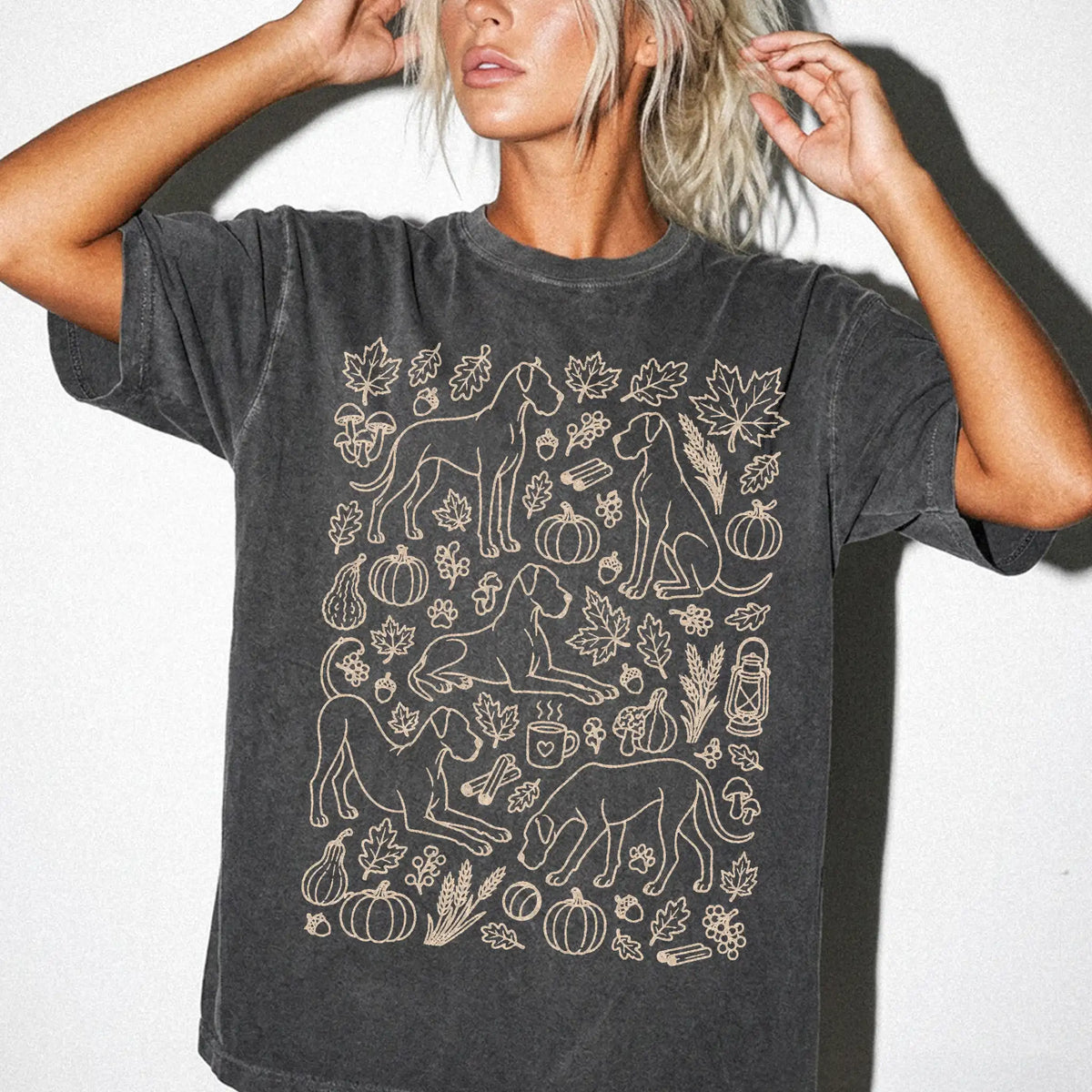 Model wearing a Pepper Comfort Colors® T-shirt with Great Dane dogs with pumpkins, leaves, acorns, and woodland details