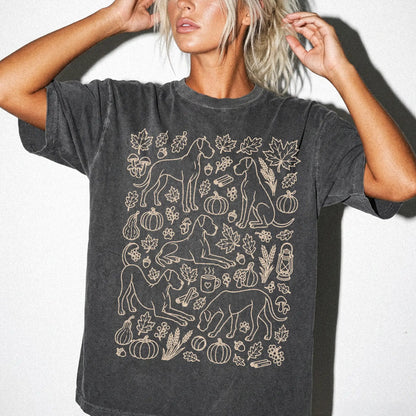 Model wearing a Pepper Comfort Colors® T-shirt with Great Dane dogs with pumpkins, leaves, acorns, and woodland details