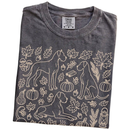 Folded Pepper Comfort Colors® T-shirt showing Great Dane dogs with pumpkins, leaves, acorns, and woodland details
