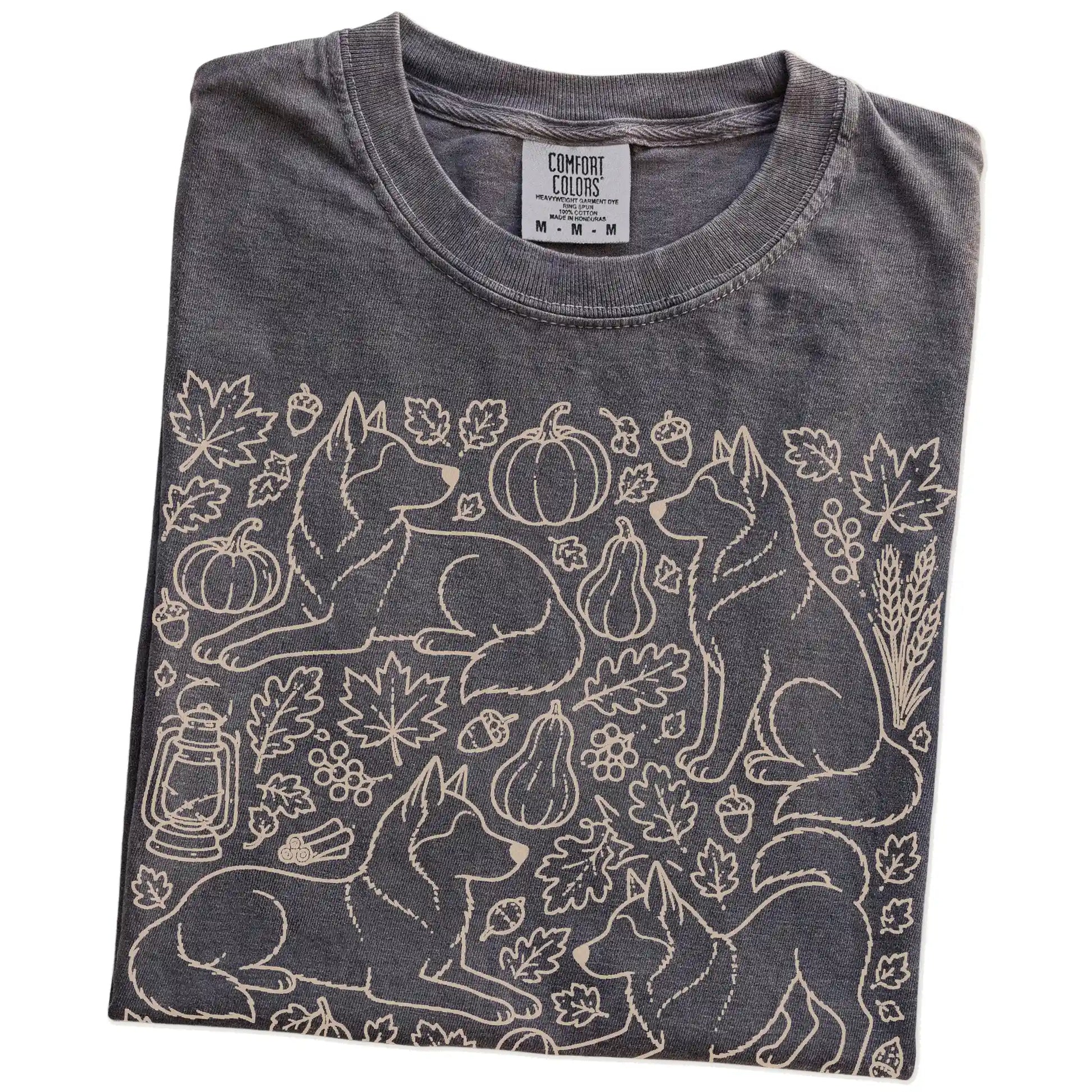 Folded Pepper Comfort Colors® T-shirt showing Husky dogs with pumpkins, leaves, acorns, and woodland details