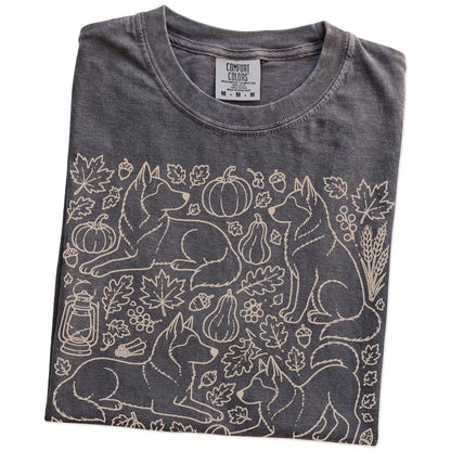 Folded Pepper Comfort Colors® T-shirt showing Husky dogs with pumpkins, leaves, acorns, and woodland details