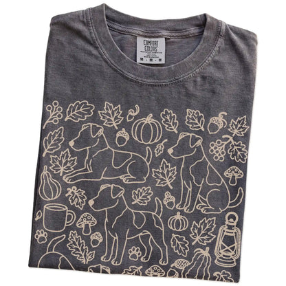 Folded Pepper Comfort Colors® T-shirt showing Jack Russell dogs with pumpkins, leaves, acorns, and woodland details