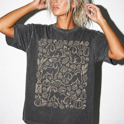 Model wearing a Pepper Comfort Colors® T-shirt with Maltese dogs with pumpkins, leaves, acorns, and woodland details