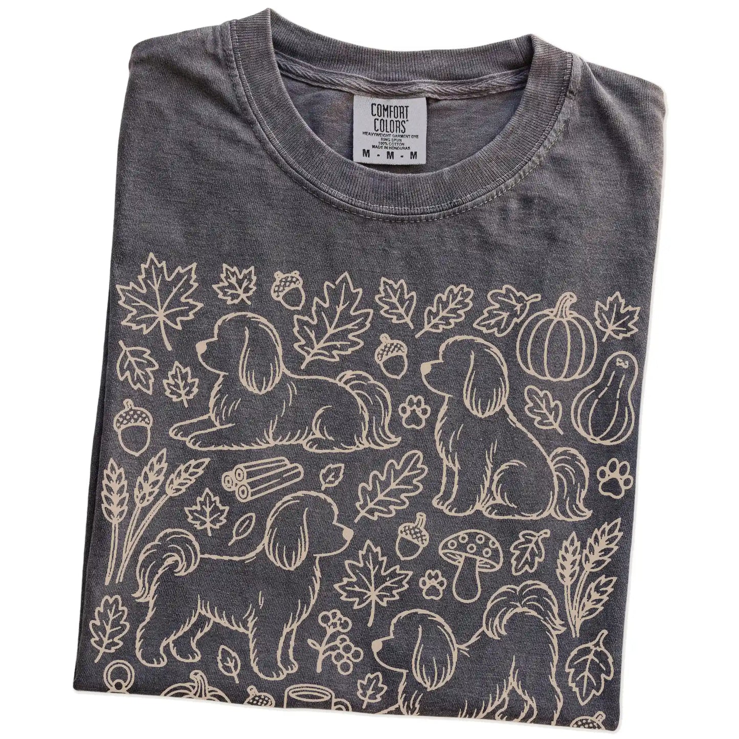 Folded Pepper Comfort Colors® T-shirt showing Maltese dogs with pumpkins, leaves, acorns, and woodland details
