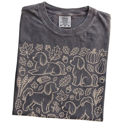 Folded Pepper Comfort Colors® T-shirt showing Maltese dogs with pumpkins, leaves, acorns, and woodland details