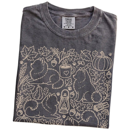 Folded Pepper Comfort Colors® T-shirt showing Pomeranian dogs with pumpkins, leaves, acorns, and woodland details