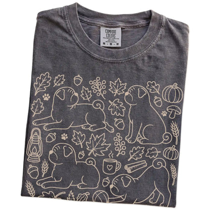 Folded Pepper Comfort Colors® T-shirt showing Pug dogs with pumpkins, leaves, acorns, and woodland details