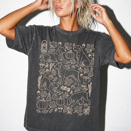 Model wearing a Pepper Comfort Colors® T-shirt with Rottweiler dogs with pumpkins, leaves, acorns, and woodland details