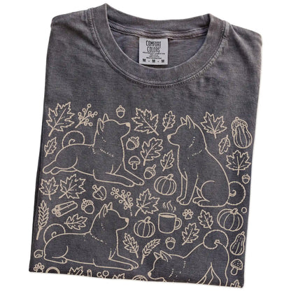 Folded Pepper Comfort Colors® T-shirt showing Shiba Inu dogs with pumpkins, leaves, acorns, and woodland details