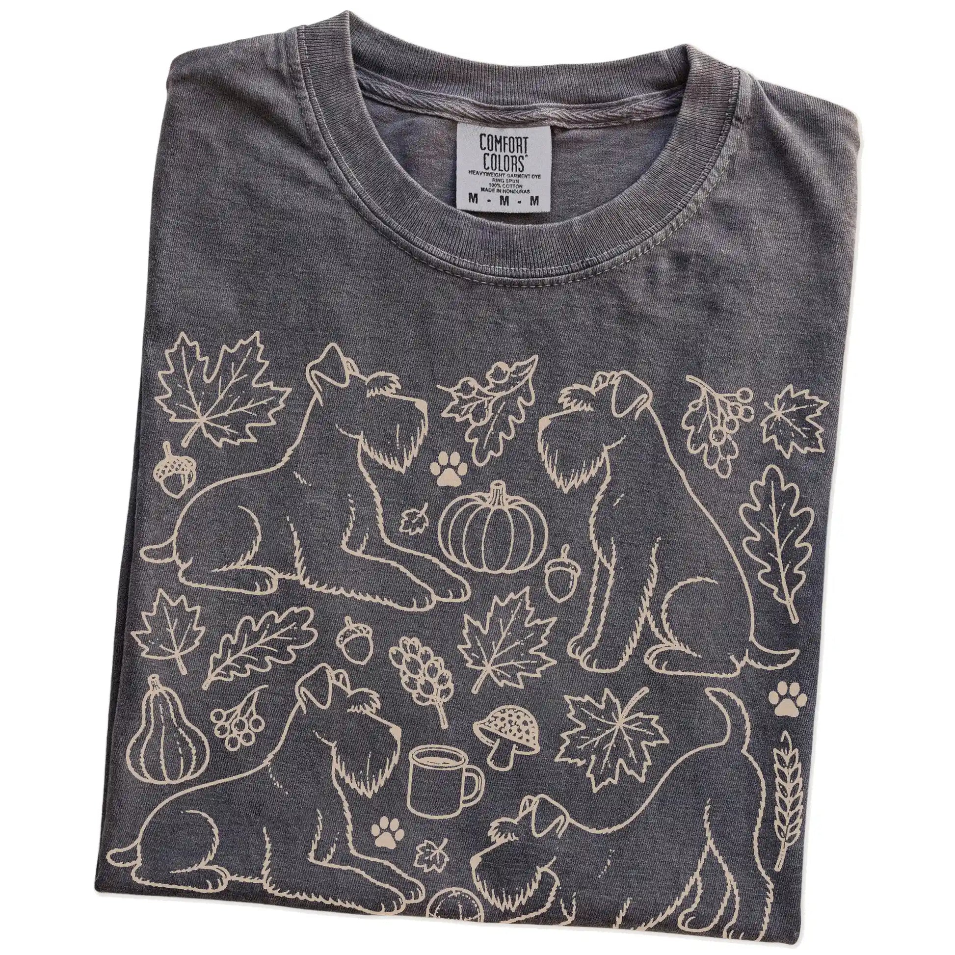 Folded Pepper Comfort Colors® T-shirt showing Schnauzer dogs with pumpkins, leaves, acorns, and woodland details