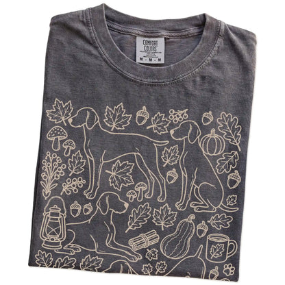 Folded Pepper Comfort Colors® T-shirt showing Weimaraner dogs with pumpkins, leaves, acorns, and woodland details