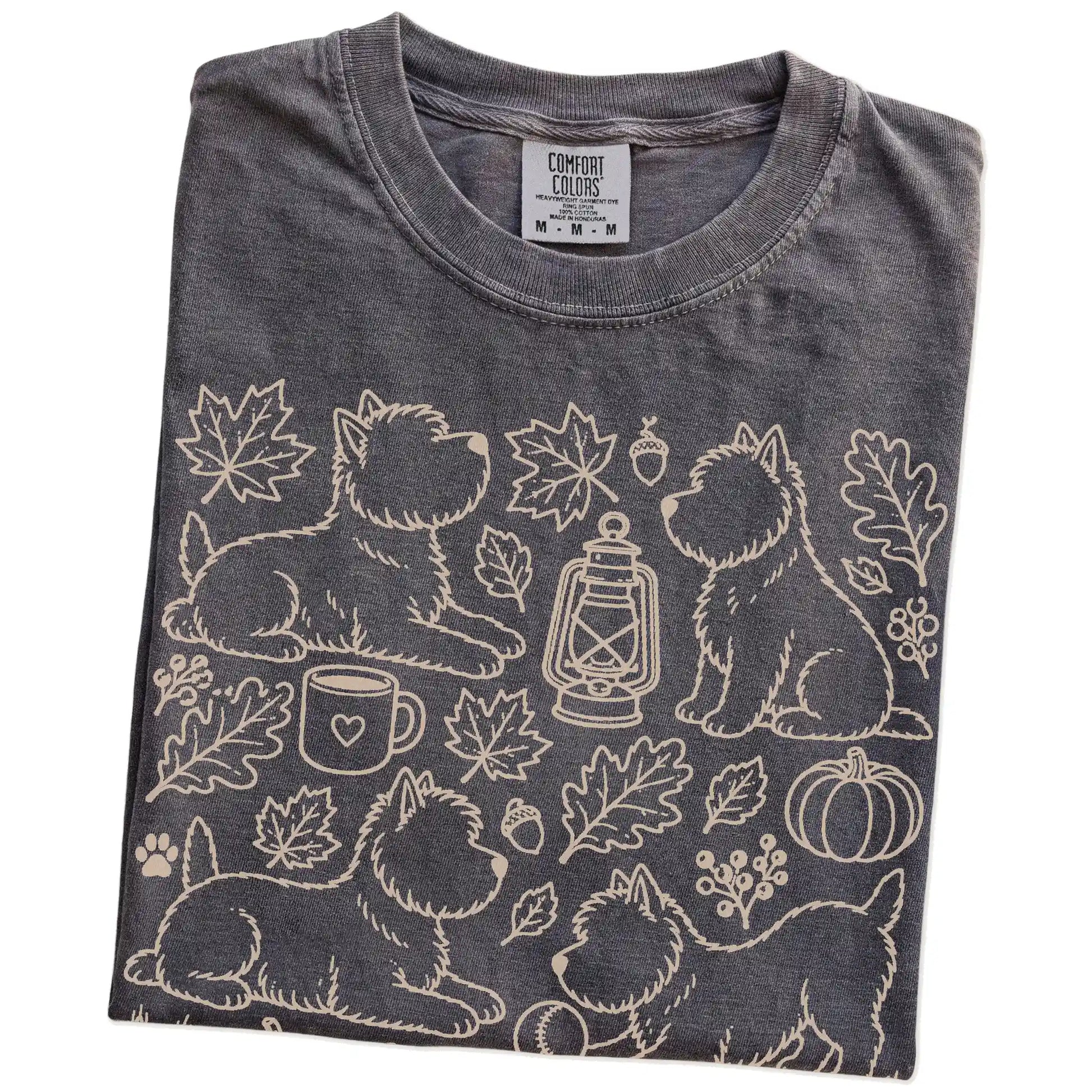 Folded Pepper Comfort Colors® T-shirt showing Westie dogs with pumpkins, leaves, acorns, and woodland details