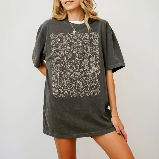 Model wearing a Pepper Comfort Colors® T-shirt with Yorkie dogs with pumpkins, leaves, acorns, and woodland details