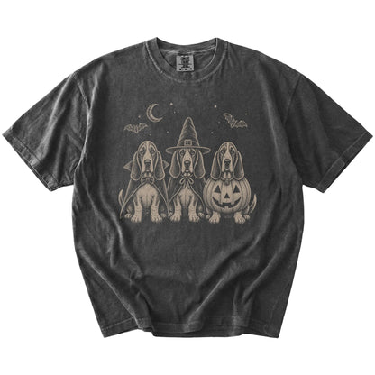 Three Basset Hound dogs dressed for Halloween beneath bats and a crescent moon on a Pepper Comfort Colors® T-shirt