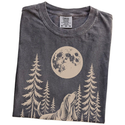 Folded Pepper Comfort Colors® T-shirt showing a Basset Hound howling beneath the moon and pine trees
