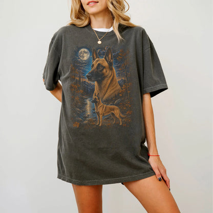 Model wearing a Pepper Comfort Colors® t-shirt featuring Belgian Malinois in a moonlit fall forest