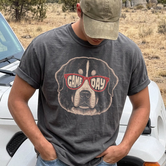 Model wearing a Pepper Comfort Colors® T-shirt with bernese mountain dog wearing red game day sunglasses