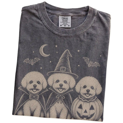 Folded Pepper Comfort Colors® T-shirt showing three Bichon Frise dogs dressed for Halloween beneath bats and a crescent moon